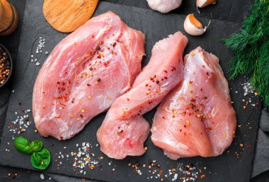 Siyah arka planda baharatlı, dereotlu ve sarımsaklı hindi filetosu. Üst görünüm, aşçılık arkaplanı.