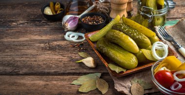 Baharat ve baharatla ahşap bir arka planda salatalık turşusu olan mutfak arka planı. Yan görünüş, manzara.