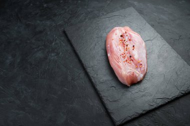 Siyah arka planda taze, çiğ et. Hindi filetosu. Kopyalama alanı olan yan görünüm.