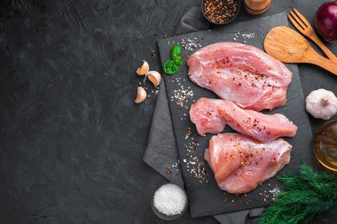 Siyah arka planda baharat ve sarımsaklı üç parça hindi fileto. Kopyalama alanı olan üst görünüm.