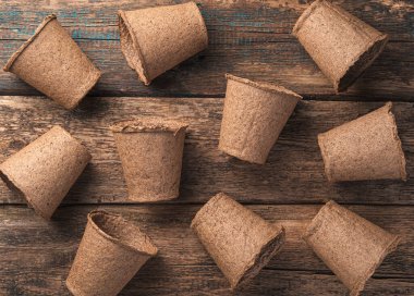 Ahşap bir masada rastgele yerleştirilmiş turba kapları olan bir arka plan. Üst Manzara. Tarım kavramı.