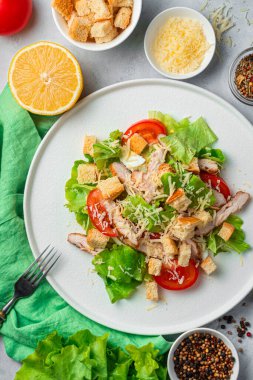 Taze Sezar salatası ve gri arka plandaki malzemeler. Renkli fotoğraf, üst manzara. Dikey oryantasyon. Aşçılık geçmişi kavramı..