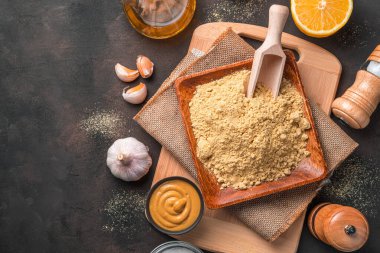 Kahverengi zemin üzerinde kuru hardal tozu ve hazır hardal. Kopyalama alanı olan üst görünüm.