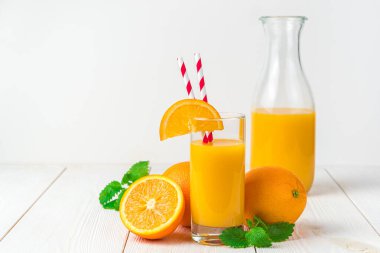 Hafif arka planda taze sıkılmış portakal suyu ve portakallar..