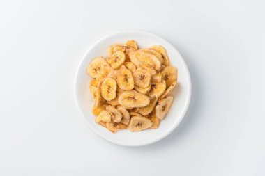 Hafif arka planda bir tabak muz cipsi. Üst Manzara. Doğal, sağlıklı tatlılar kavramı.