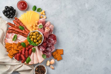 Hafif arka planda zeytin, sos, baharat ve sarımsaklı et ve peynir lezzetleri. Şarküteri tahtası