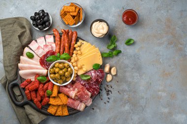 Söğüş et, peynir, zeytin, kraker, fesleğen ve soslar gri arka planda kopyalayacak yer var. Üst görünüm, yatay.