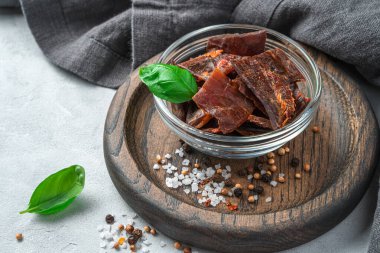 Biber, tuz ve gri arka planda taze fesleğenli kurutulmuş et. Yan görünüm, yakın plan.