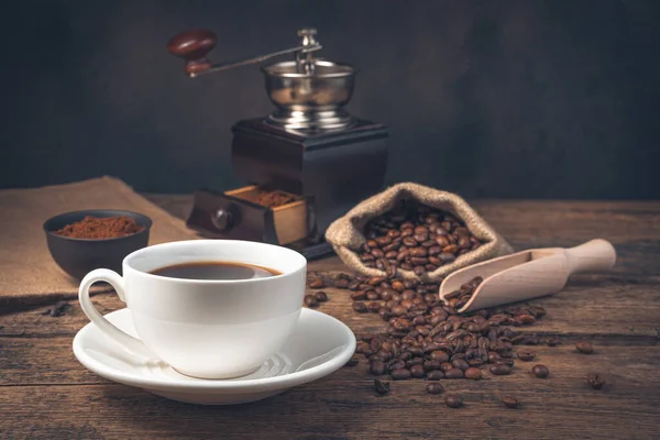 A cup of coffee on a vintage brown background with a coffee grinder. Side view, horizontal.