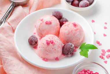 Yaz kremalı meyveli tatlı. Hafif arka planda vişneli dondurma topları. Yan görünüm, yakın plan.