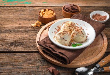 Soğuk tatlı, kurabiyeli dondurma ve ahşap arka planda çikolata. Yan görünüm, boşluk kopyala.