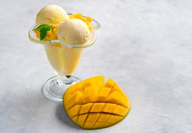 Gri arka planda dondurulmuş meyve ve kremalı tatlı. Mango dondurması ve taze meyve, fotokopi alanı ile yan görünüm.