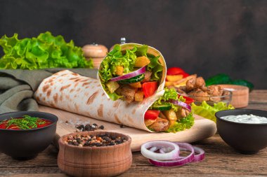 Kahverengi bir zemin üzerinde et ve sebzeli iki geleneksel oryantal shawarma yemeği. Fast food, fast food.