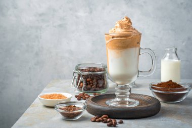 Dalgona kahvesi ve gri arka plandaki malzemeler. Krem şantili kahve ve süt..