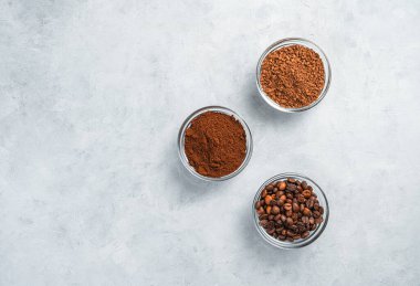 Gri arka planda fincanlarda anında, öğütülmüş ve tahıllı kahve. Kopyalama alanı olan kahve arkaplanı.