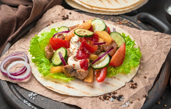 Grilled meat, French fries, fresh vegetables and sauces on a brown background. Preparation of tacos, shawarma, burritos. Close-up, side view.