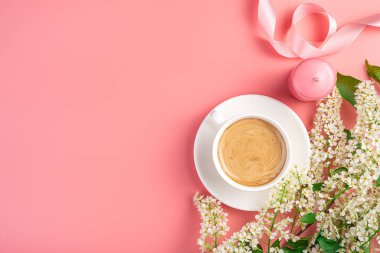 Kapuçino fincanı ve pembe arka planda mumları olan çiçek arkaplanı. Üst görünüm, alanı kopyala.