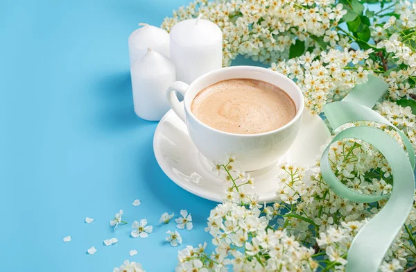 Flowers, coffee and candles on a light blue background. Side view, copy space.