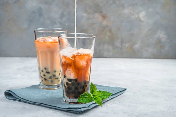 Thé à bulles, préparation d'une boisson taïwanaise avec tapioca, lait et glace sur fond gris. — Photo