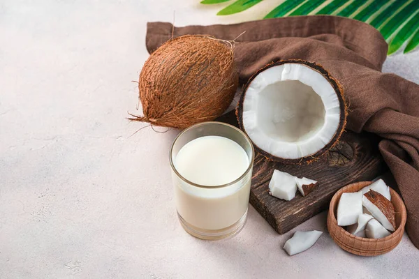 Fresh natural coconut milk and coconut on a light pink background. Vegetable milk. Copy space.