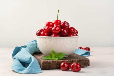 Bej arka planda bir kasede taze, sulu kirazlar. Yan görünüm, yakın plan.