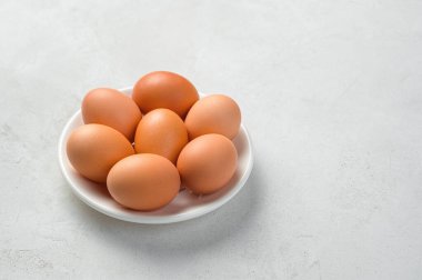 Gri arka planda beyaz tabakta tavuk yumurtası. Yan görünüm, boşluk kopyala.