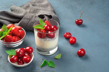 Koyu arkaplanda taze böğürtlen ve meyveli sağlıklı bir tatlı. Çilekli ve kirazlı kremalı puding. Yan görünüm, boşluk kopyala.
