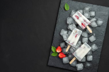 Siyah arka planda tahta bir çubuğun üzerinde chia tohumu ve çilekli üç dondurma. Sağlıklı kremalı tatlı. Boşluğu kopyala.