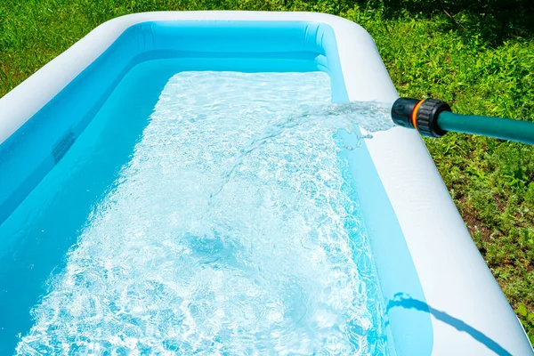 Наполните надувной бассейн водой. Бассейн в летнем саду. — стоковое фото