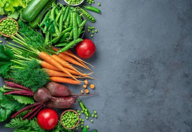 Taze havuç, kabak, bezelye, domates ve yeşiller koyu mavi arka planda..