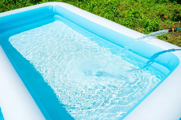 Der Sommergarten-Pool wird mit Wasser aus einem Schlauch gefüllt. — Stockfoto