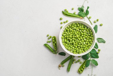 Gri arka planda bezelye kabukları ve yapraklı taze bezelyeler. Yatay görünüm, kopyalamak için boşluk.