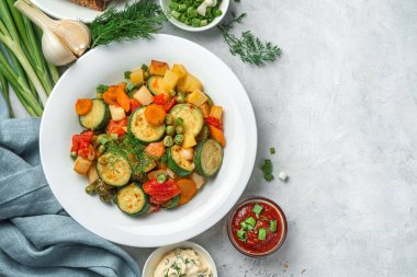 Gri arka planda beyaz bir tabakta haşlanmış sebzeler. Sağlıklı, vejetaryen yemekleri..