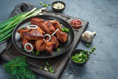 Koyu gri arka planda soğanlı ve otlu kızarmış et. Kebap, barbekü. Yan görünüm, kopyalamak için boşluk.