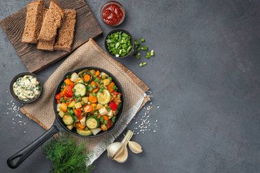 Sebze yahnisi, çavdar ekmeği ve gri-kahverengi arka planda taze otlarla sağlıklı bir öğle yemeği. Üst görünüm, alanı kopyala.