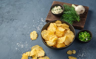 Yeşil cipsler ve koyu arkaplanda ekşi krema. Aperatif. Yan görünüm, kopyalamak için boşluk.