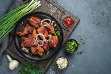 Koyu gri bir arka planda yeşil soğanlı kızarmış et, dereotu ve sos. Üst görünüm, alanı kopyala.