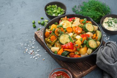 Gri-mavi arka planda sebze güveci ile kızartma tavası. Yan görünüm, kopyalamak için boşluk.