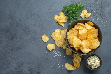 Ekşi kremalı ev yapımı cips ve koyu gri arka planda dereotu kopyalamak için yer var. Yatay görünüm.