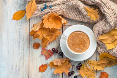 Sonbahar arkaplanı, bir fincan kahve, bej arka planda bir süveter ve yeşillik. Üst görünüm, alanı kopyala.