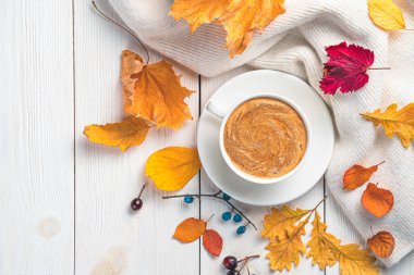 Kahve, sıcak bir süveter ve beyaz arka planda sonbahar yaprakları..