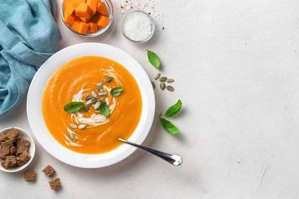 Sopa de calabaza saludable de otoño con semillas de calabaza y crema sobre un fondo gris claro. — Foto de Stock