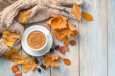 Bir fincan kahve, sıcak bir süveter ve yeşillikle rahat bir sonbahar arkaplanı..