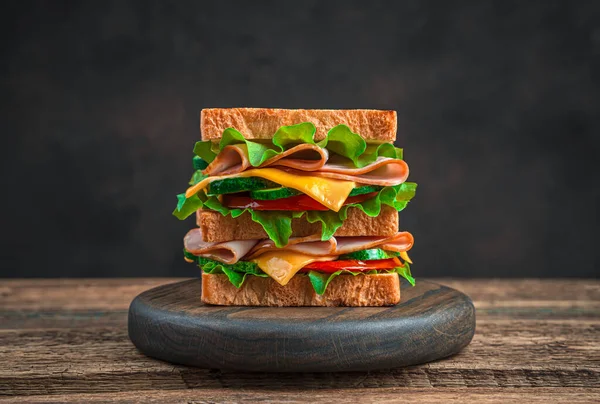 Double club sandwich with cheese, ham, tomato and cucumber on a brown background. — Stock Photo, Image
