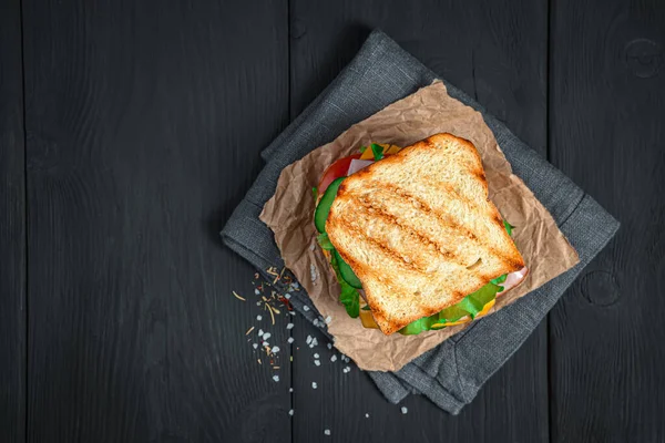 Grilled sandwich with vegetables and ham on a black background. — Stock Photo, Image