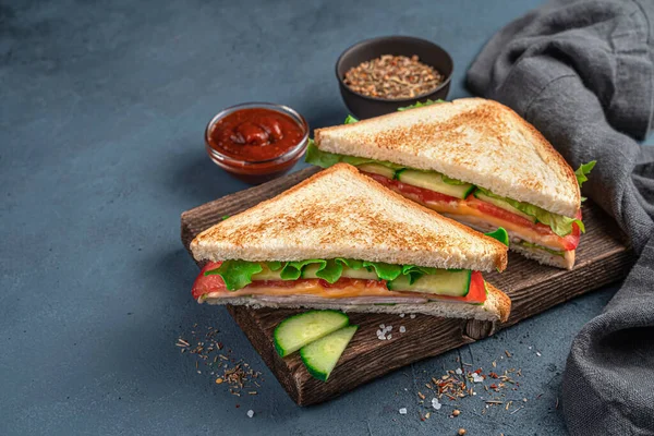 Two sandwiches with ham, cheese, tomatoes, cucumbers and lettuce on a dark gray-blue background with space for copying. — Stock Photo, Image