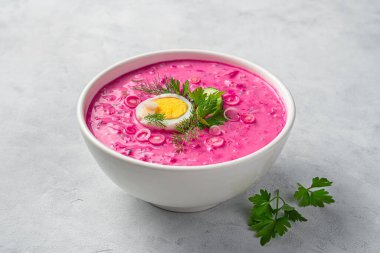 Bir tabak soğuk pancar çorbası, yumurta ve gri arka planda bitkiler. Yan görünüm, yakın plan.