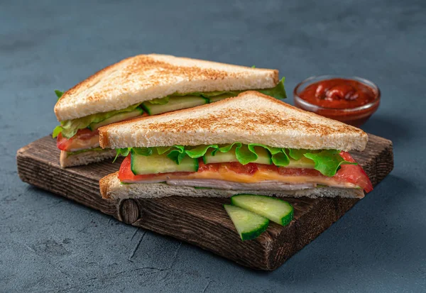 Panini club con prosciutto, formaggio e verdure su sfondo blu scuro. — Foto Stock