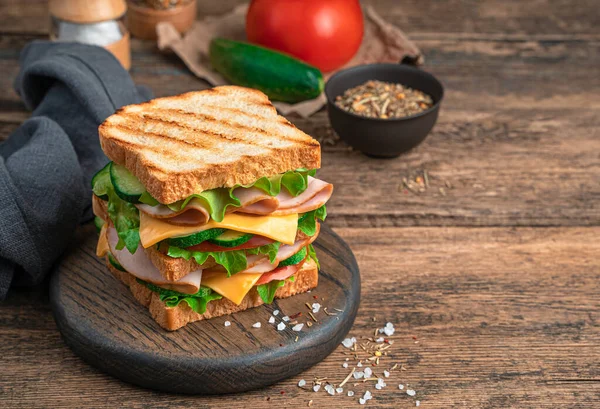 Sandwich with vegetables and ham on a wooden, brown background. — Stock Photo, Image