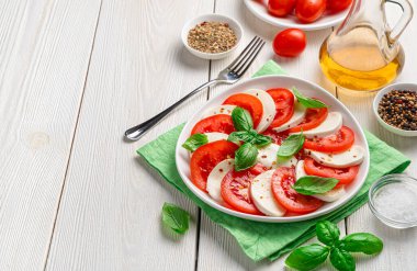 Olgun domatesli, mozzarella peynirli, fesleğenli ve zeytinyağlı nefis caprese salatası. İtalyan mutfağı. Yan görünüm, kopyalamak için boşluk.